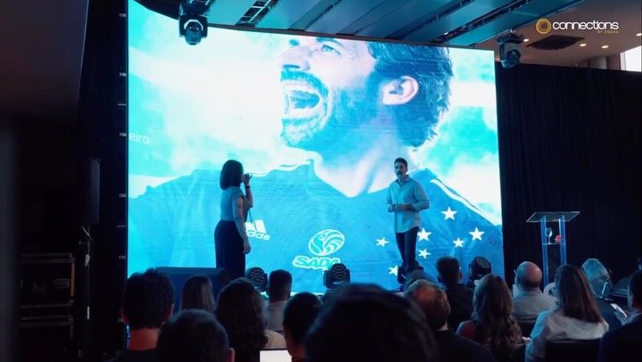 Palco de abertura do SQUAD Connections, com a plateia de frente para o telão